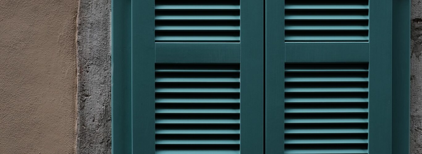 plantation shutters brighton - Teal-shuttered-window-on-wall