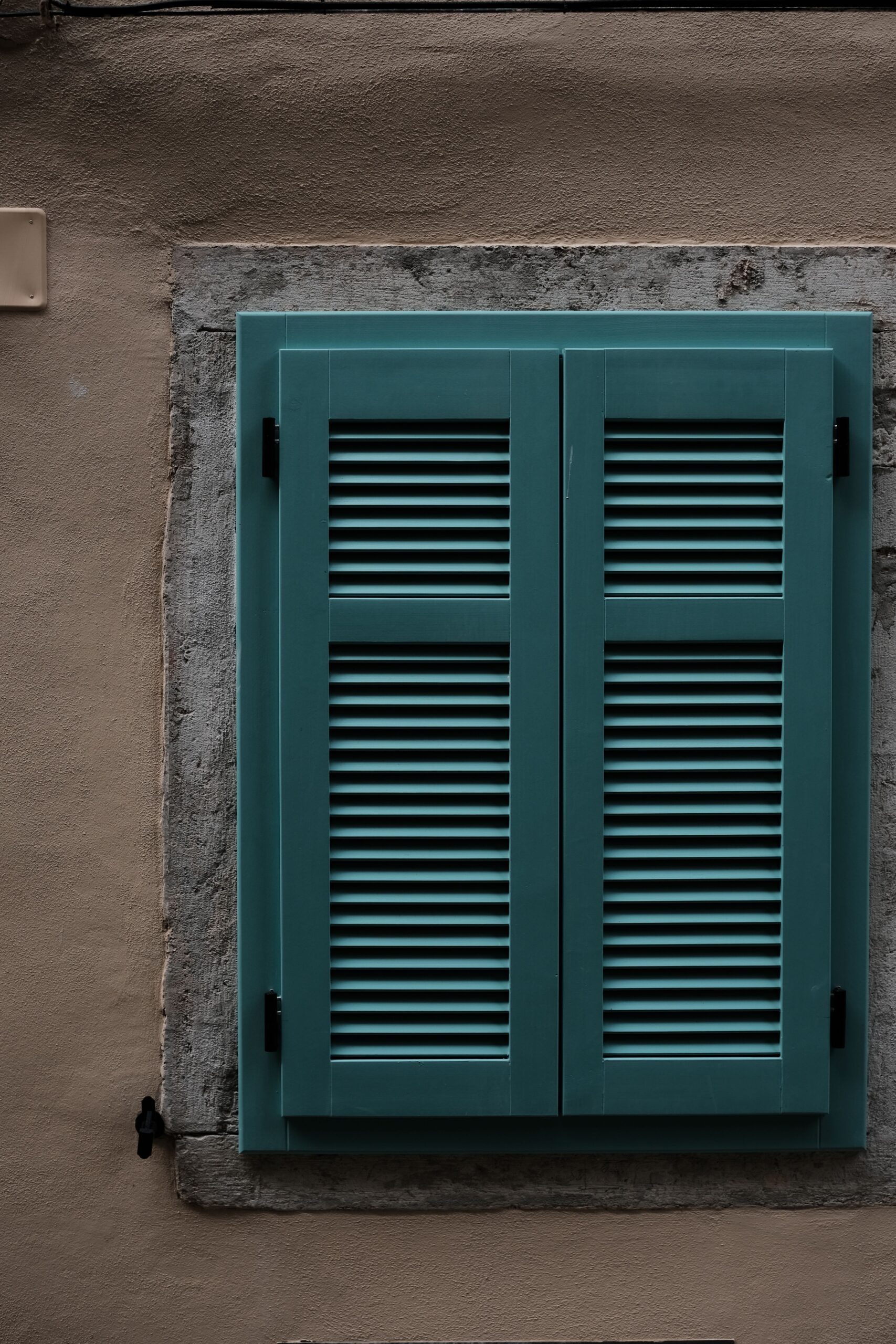 plantation shutters brighton - Teal-shuttered-window-on-wall